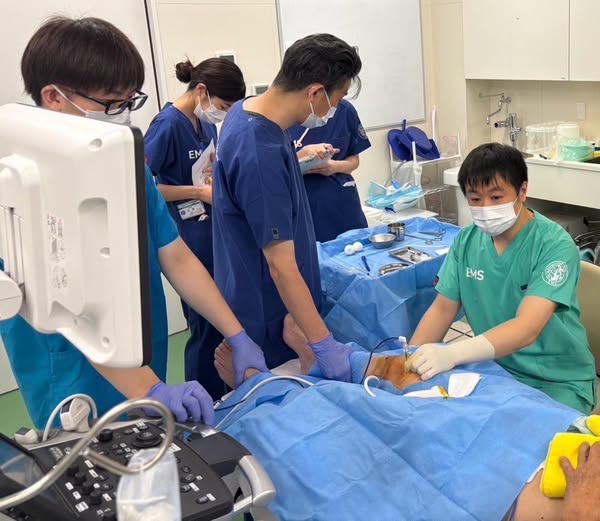 4人、病院、、「EM Cà EMS」というテキストの画像のようです